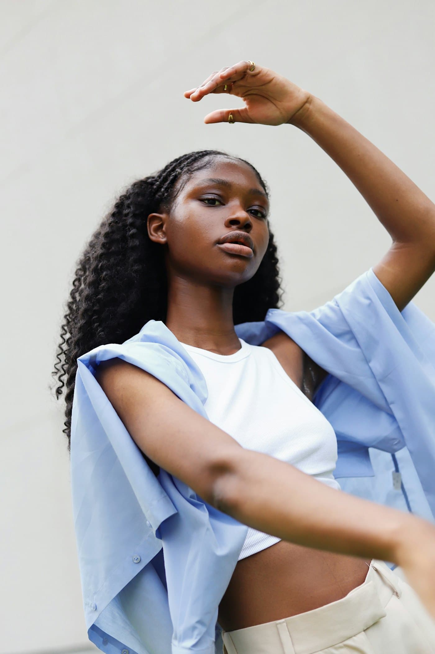 A creator in a white top and pale blue shirt posing against a white wall