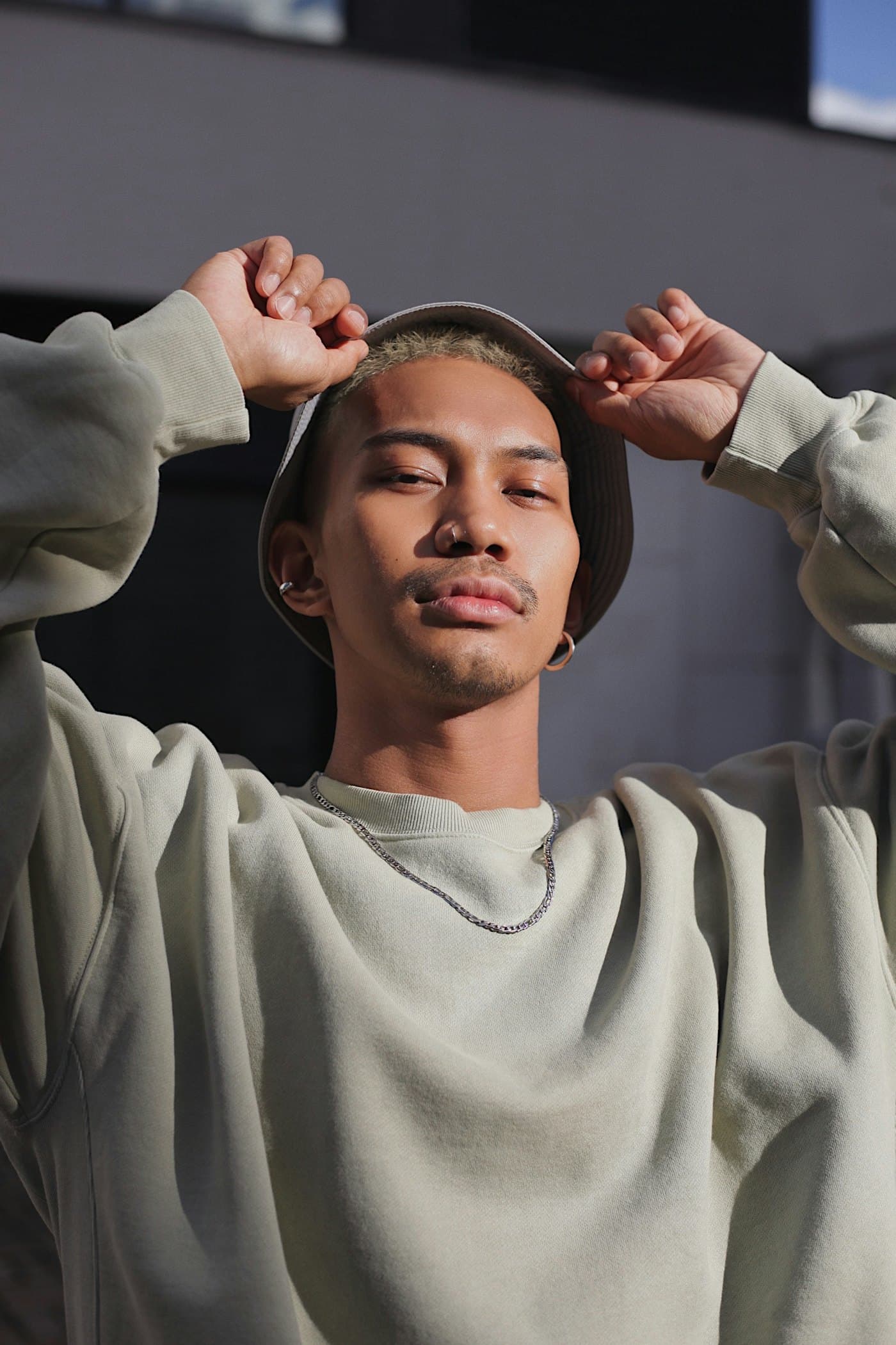 A creator in a bucket hat and grey sweatshirt looking at the camera